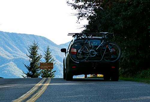 Car with bicycles on a rack driving on a mountainous road.