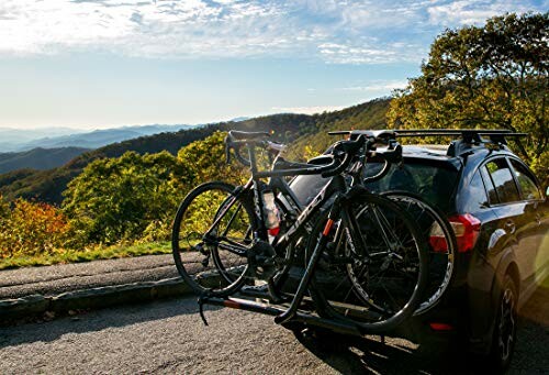 Car with bike rack on mountain road.