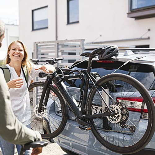 Woman smiling while loading a bicycle onto a car bike rack.